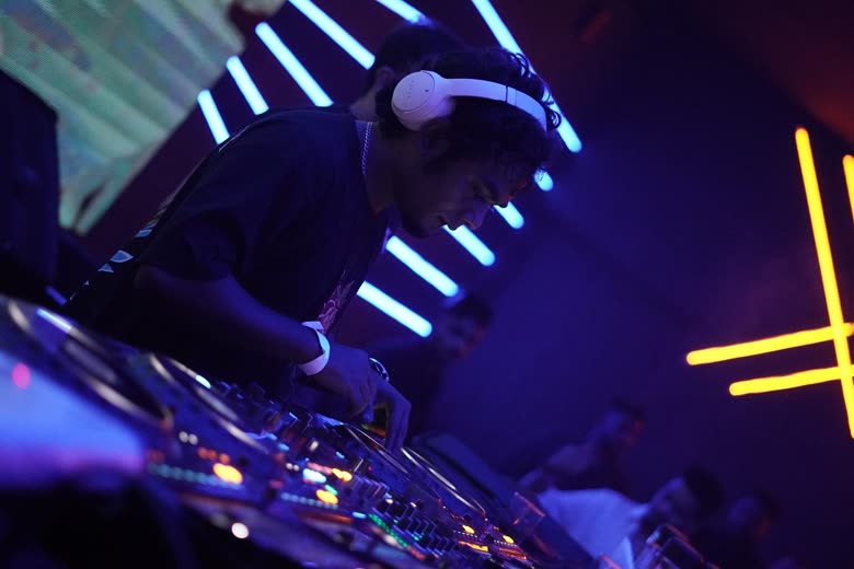 Protonix at the mixer, headphones on, during a live set